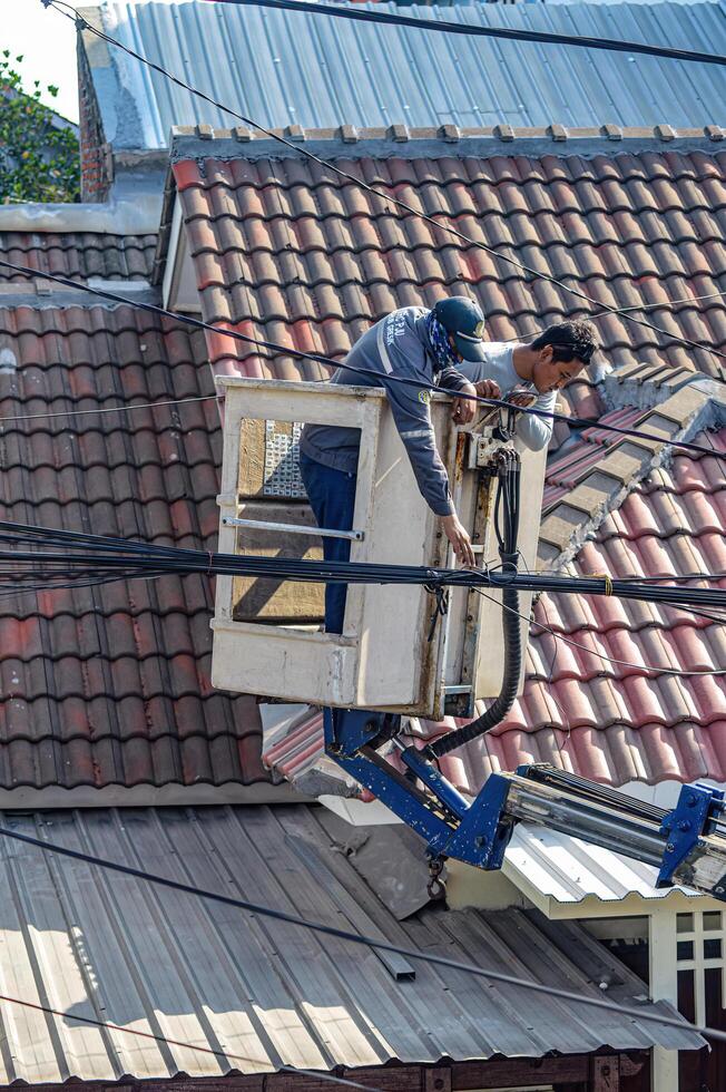 The Public Works Department is organizing messy telecommunications and electrical cables using a sky lift car, Indonesia, 19 December 2023. photo