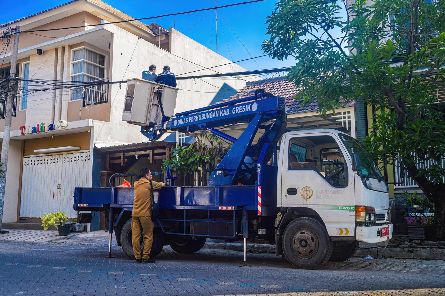 el público trabajos Departamento es organizando sucio telecomunicaciones y eléctrico cables utilizando un cielo levantar auto, Indonesia, 19 diciembre 2023. foto