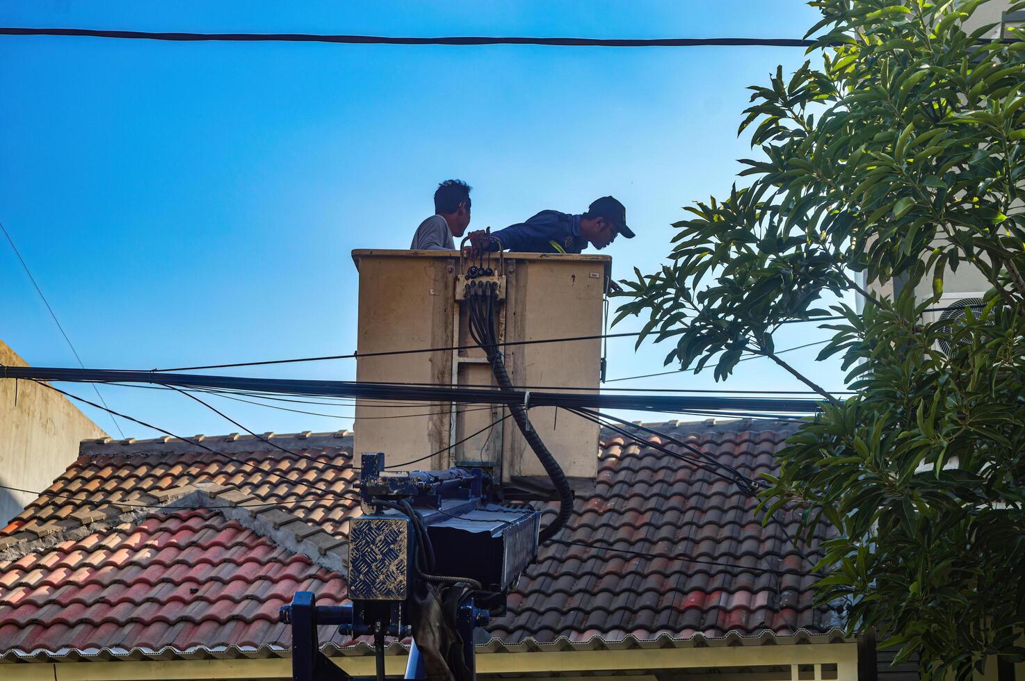 The Public Works Department is organizing messy telecommunications and electrical cables using a sky lift car, Indonesia, 19 December 2023. photo