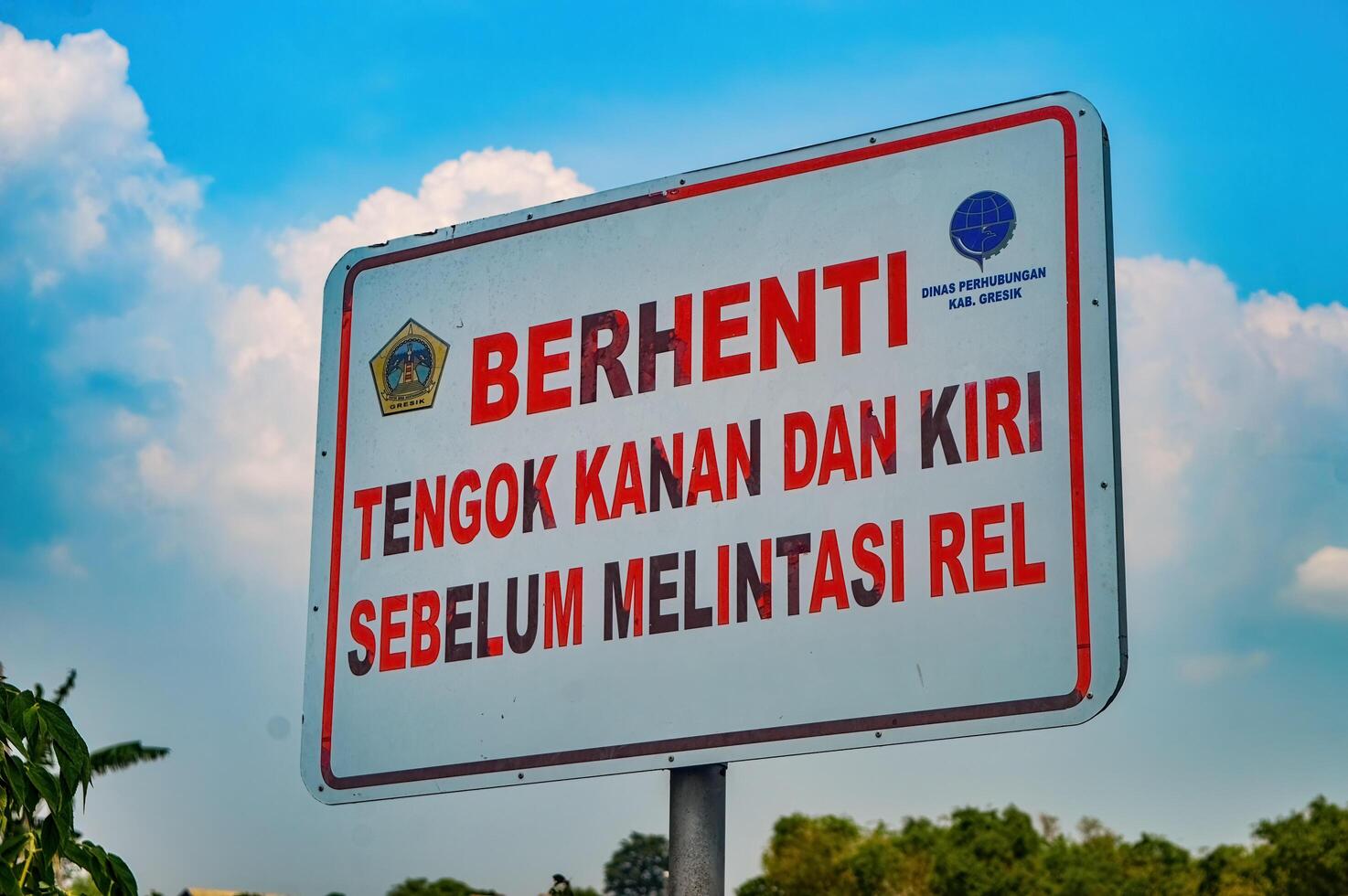 a warning sign that says stop, look left and right before crossing the tracks, Indonesia, 16 December 2023. photo