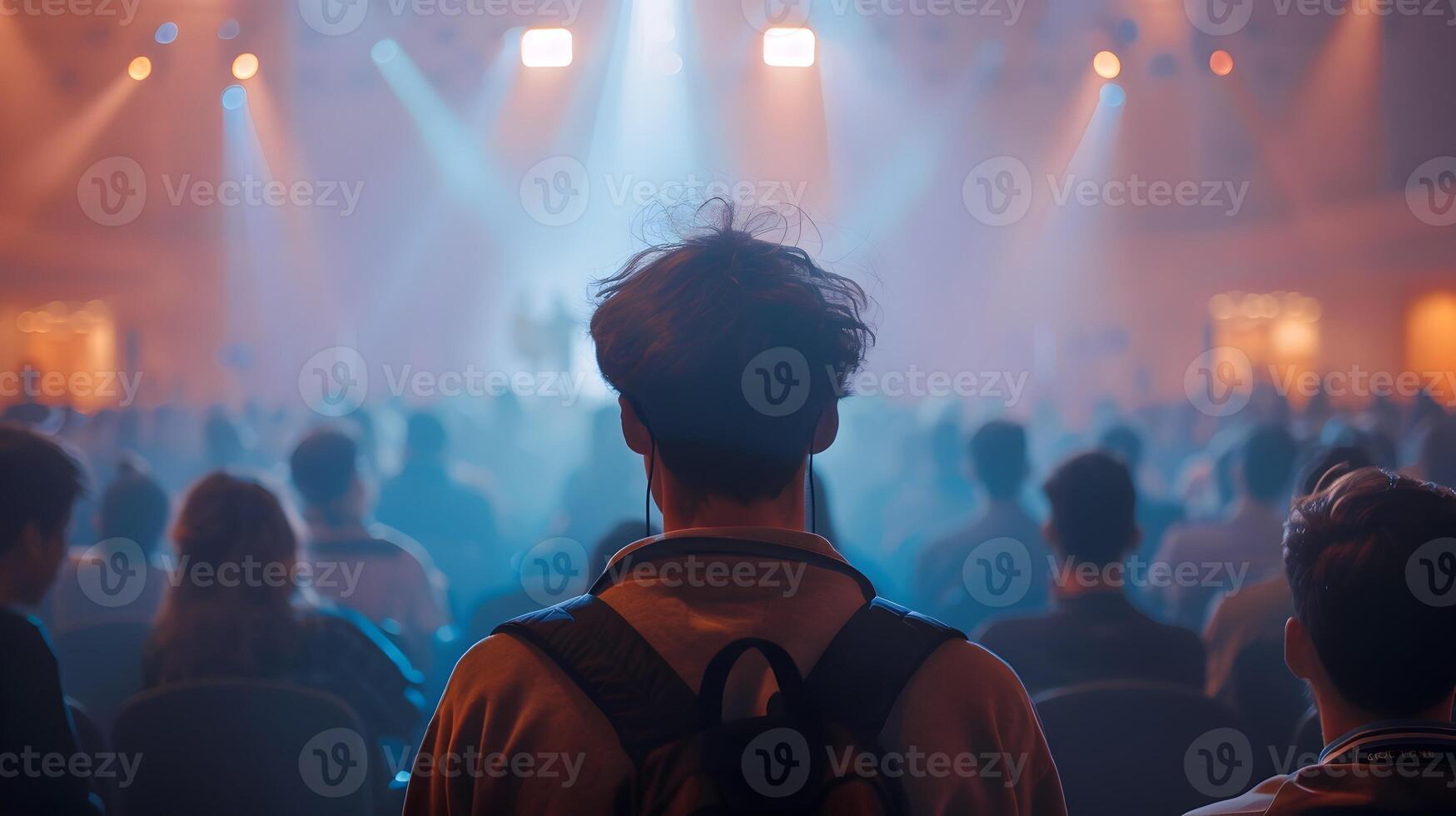 AI generated Young Man Illuminated at Concert Hall with Backpack, To convey a sense of excitement and curiosity at a next-gen AI convention, as delegates intently photo