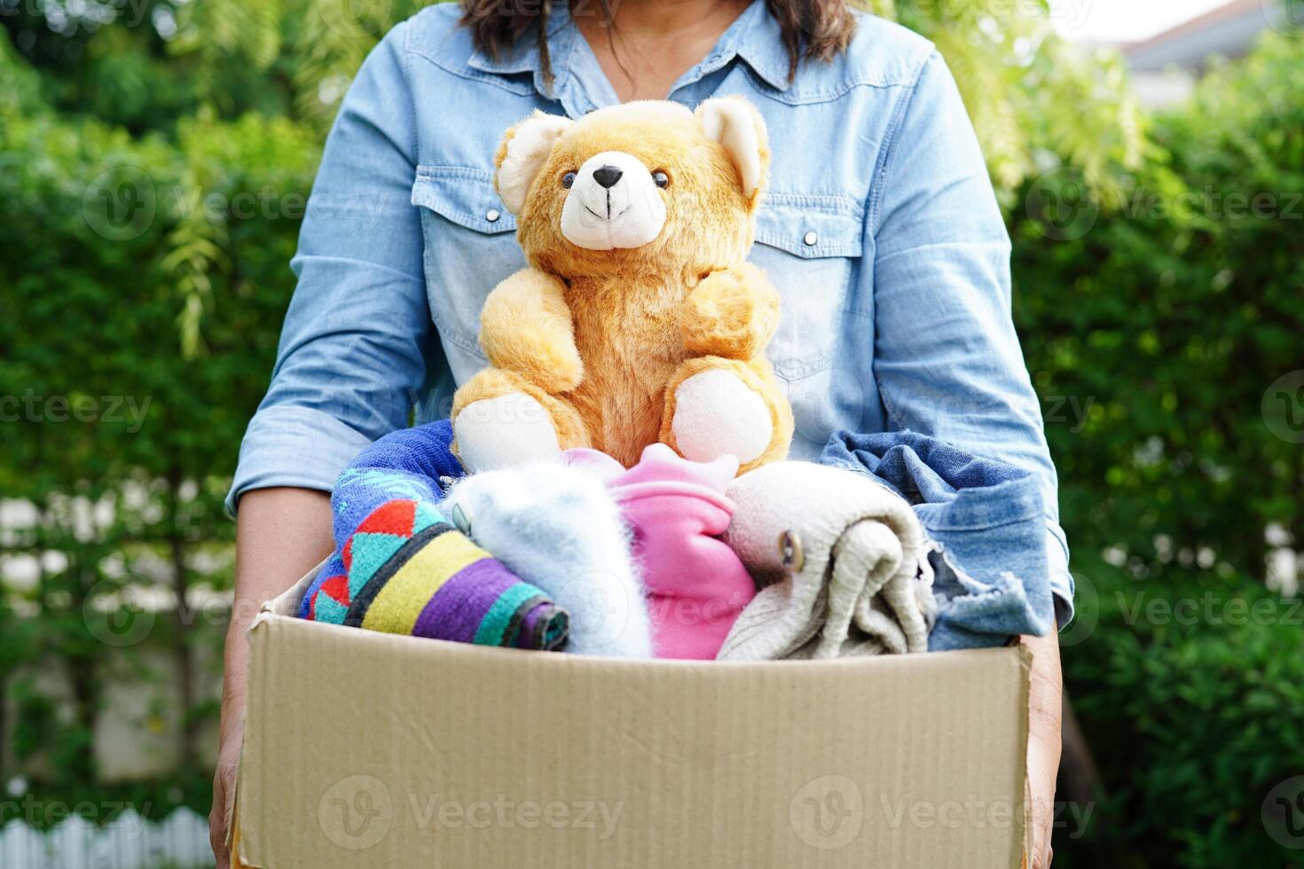 Volunteer collect cloth and doll in cardboard box to donate. photo