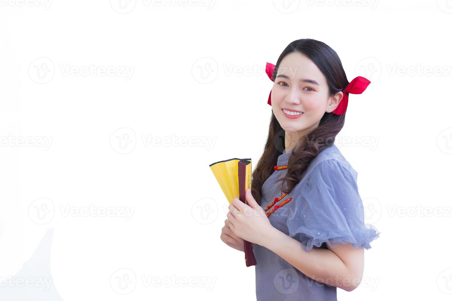 Young asian beautiful woman in gray Qipao dress with red bow is smiling holding fan on the street in China town Thailand while isolated white background. photo