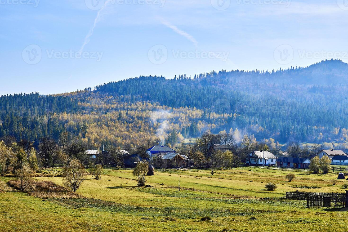 pequeño pueblo con campos a el pie de el otoño montañas foto