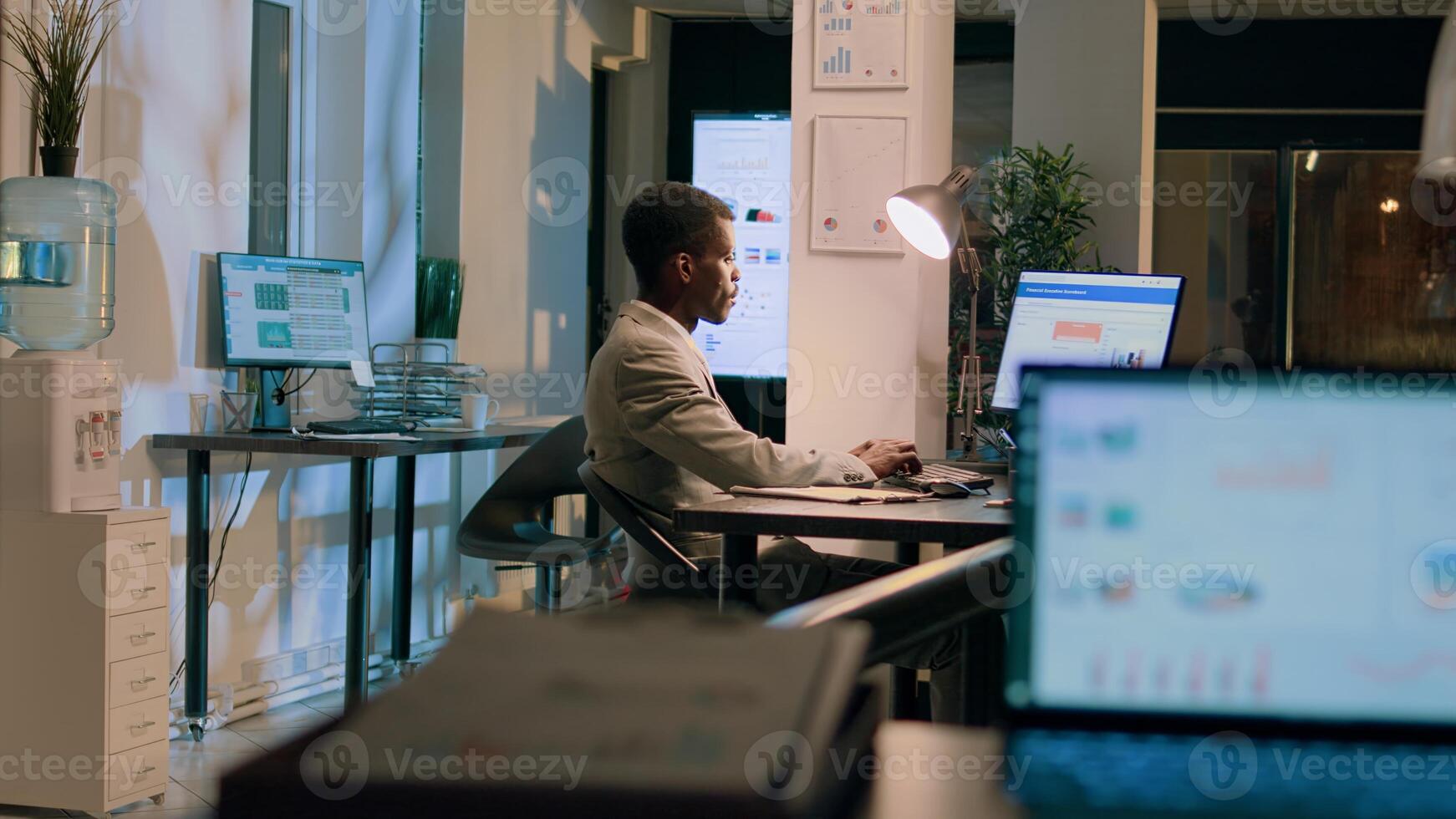 Bipoc coworkers auditing financial payroll reports and statistics on computer screen during nightshift. Adept businessmen working overnight on important project due tomorrow photo