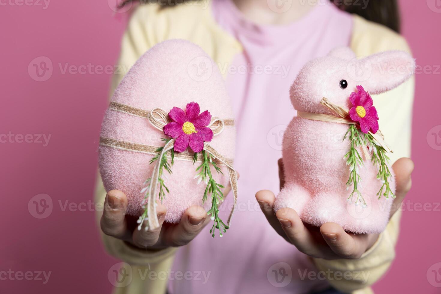 Cute small kid presenting her handmade decorated ornaments, adorable pink egg and a stuffed rabbit in studio. Little girl smiling and feeling excited about easter celebration event. Close up. photo