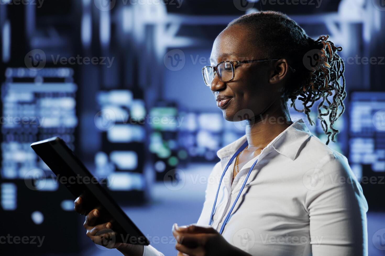 Upbeat admin in data center uses tablet to prevent system infrastructure overload. Precise expert between blade servers ensuring enough network bandwidth for smooth operations photo