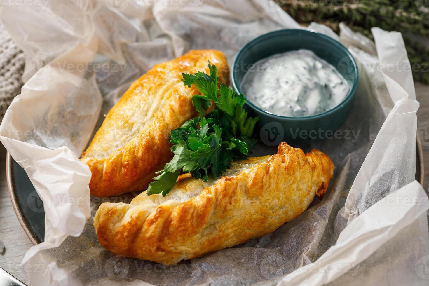 Baked buns with sour cream and parsley on parchment paper photo