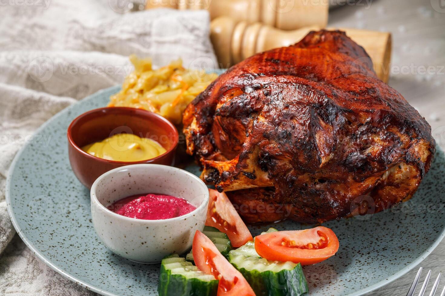 pork knuckle with vegetables and sauce on a plate, closeup photo