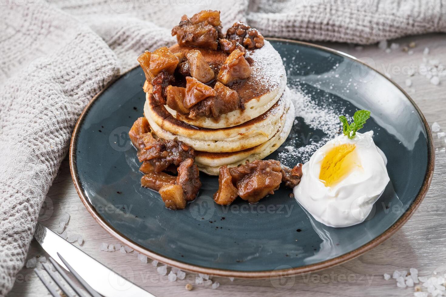 Pancakes with caramelized apples and sour cream on a plate photo