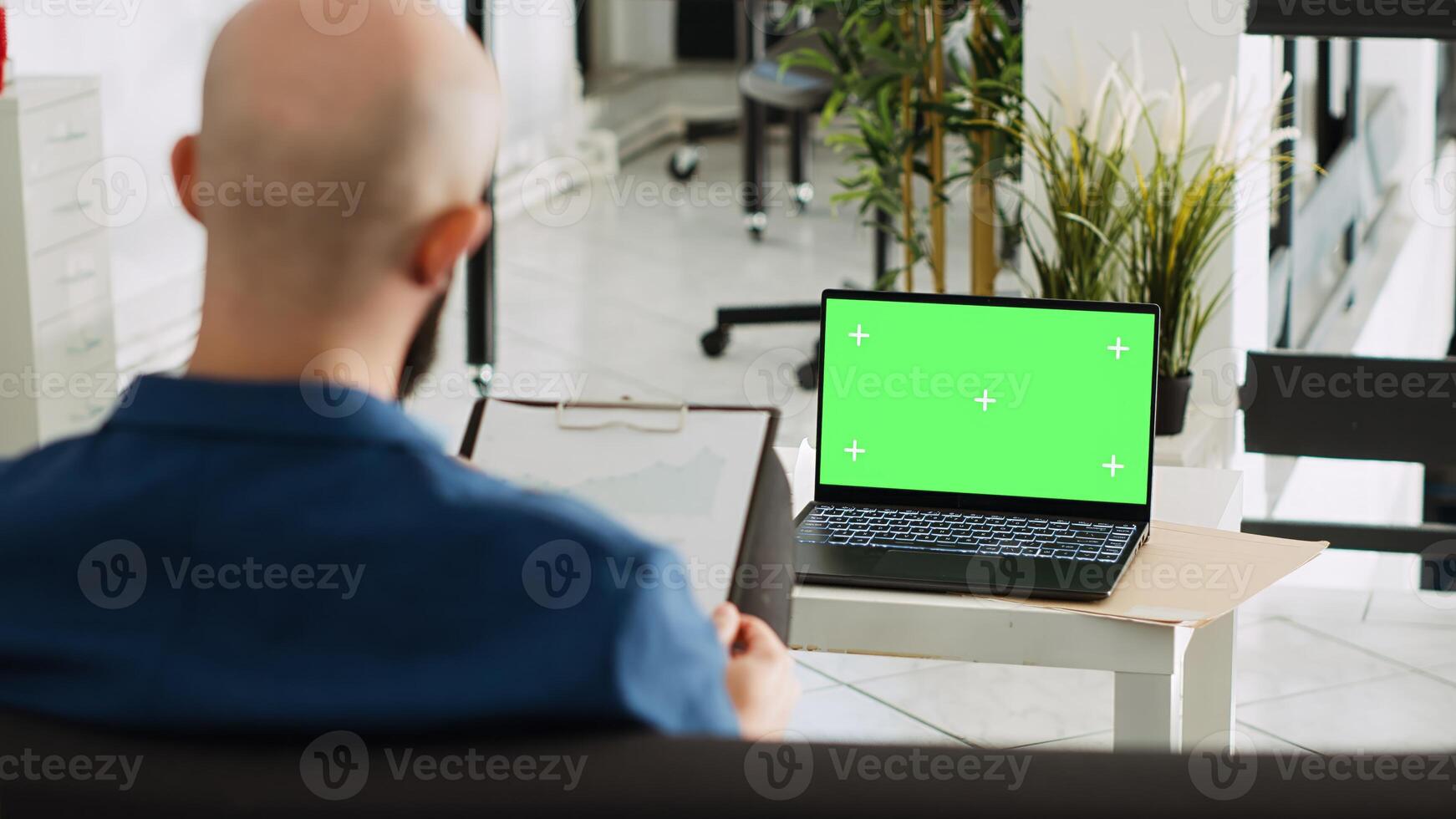 Company worker with greenscreen display reviewing documents, looking at chromakey blank template in open space. Businessman using laptop and analytics for successful research plan. photo