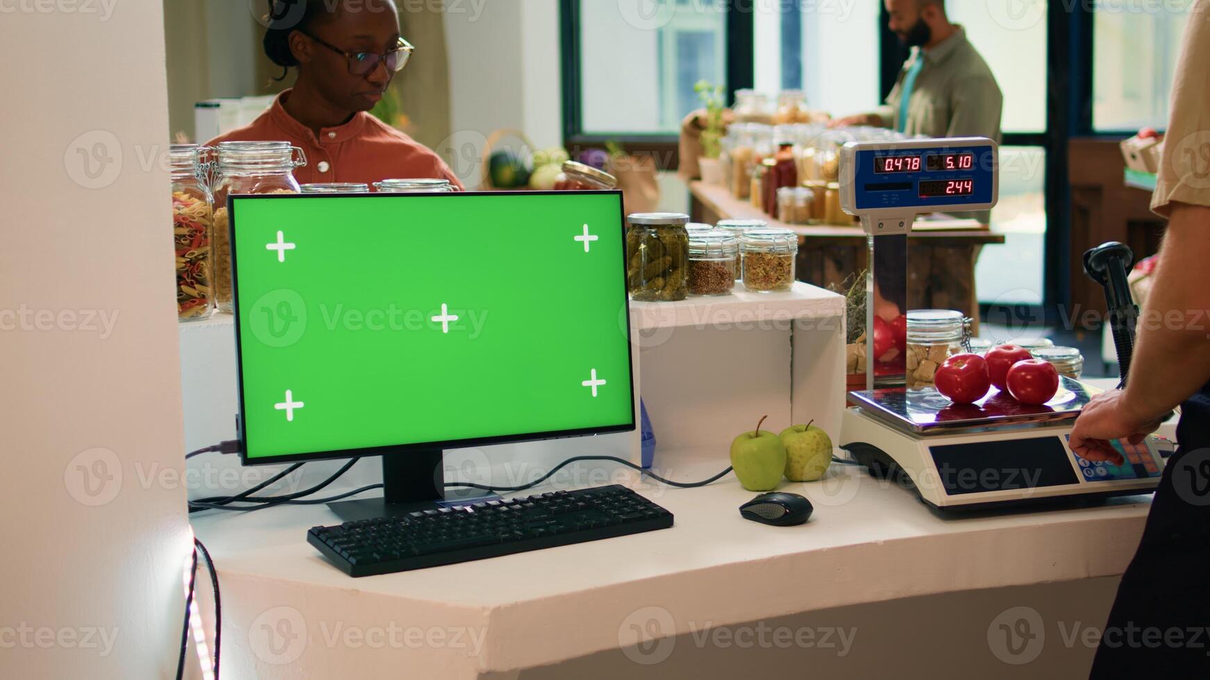 Vendor at checkout uses greenscreen on computer, showing isolated chromakey display on desktop monitor. Young adult small business owner advertises sustainable lifestyle with blank mockup. photo