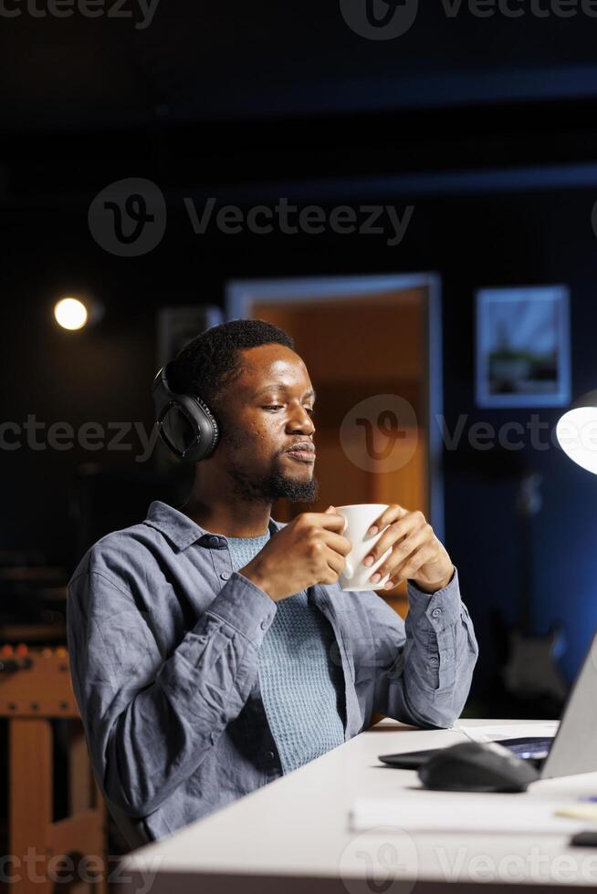 Young adult attends training online program from home, listening to teacher explaining business administration terms. African american student learning management, listening to podcast. photo