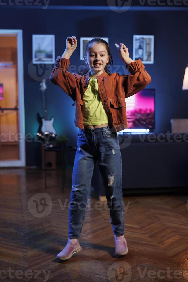 Popular child takes part in viral dance trend after seeing favorite celebrities doing it, filming family channel video in apartment for children audience. Smiling kid does trendy dancing challenge photo