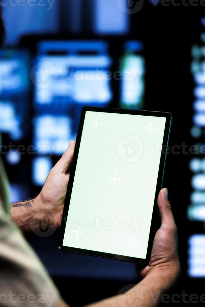 Developer with chroma key tablet using it for checking on high bandwidth dedicated game servers, used to accommodate incoming traffic of internet users joining from worldwide locations photo