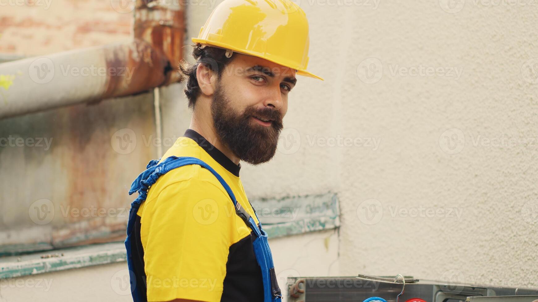 Portrait of qualified serviceman working on broken air conditioner, using power drill to disassemble condenser metal coil panel. Proficient engineer dismantling hvac system to check for freon leaks photo