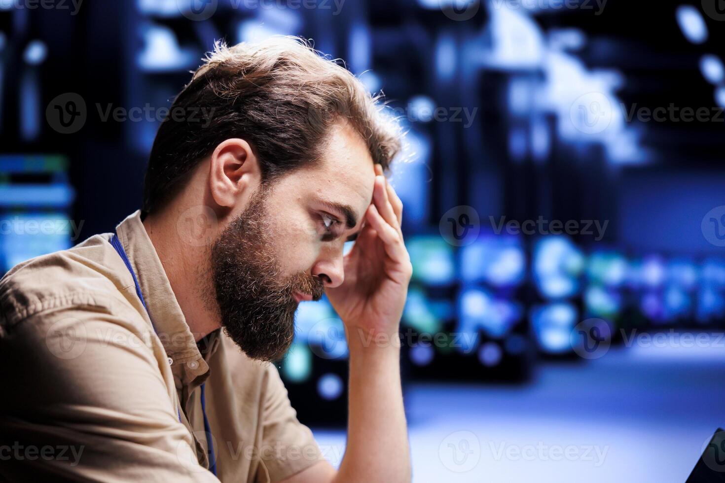 Overworked engineer struggling to maintain uptime in high tech data center. Hardworking technician upset about server hub infrastructure crashing, trying to repair equipment photo