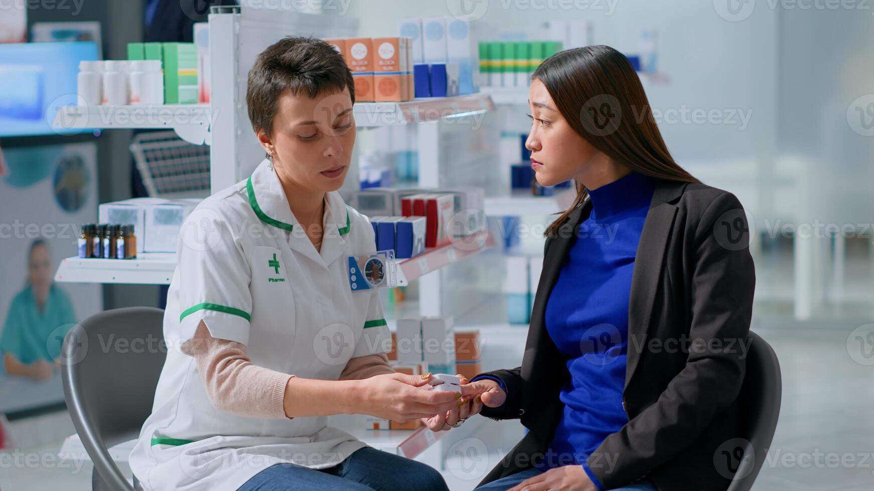 Healthcare expert clipping asian patient finger using pulse oximeter, monitoring level of blood oxygen saturation and heart rate during appointment in chemist shop offering full range of services photo