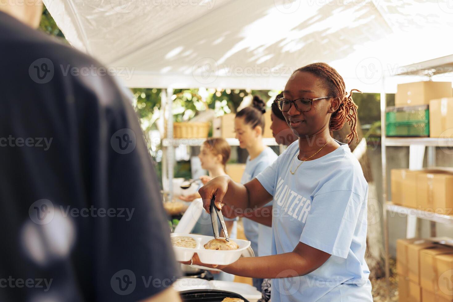 africano americano mujer servicio gratis comida a el pobre, necesitado individual a un al aire libre comida banco. hembra voluntarios alimentación y Proporcionar apoyo a el hambriento y Menos privilegiado a un Vagabundo refugio. foto
