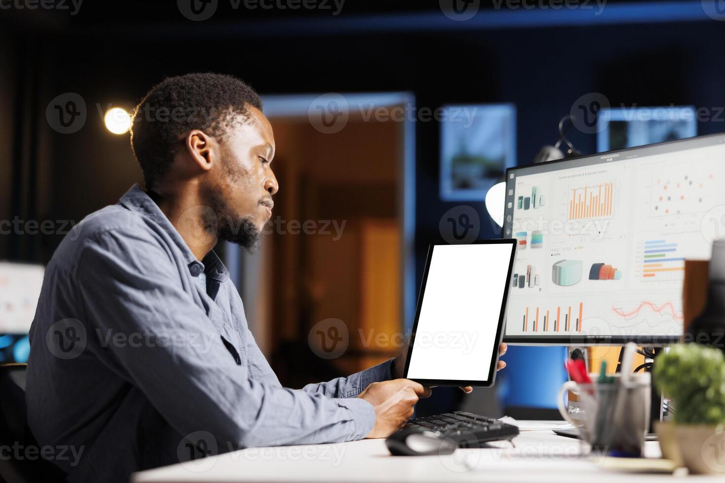 Using mobile device with white screen layout, enterprise consultant predicts target value and yearly revenue. African american supervisor interested in electronic metrics and fiscal schematics. photo