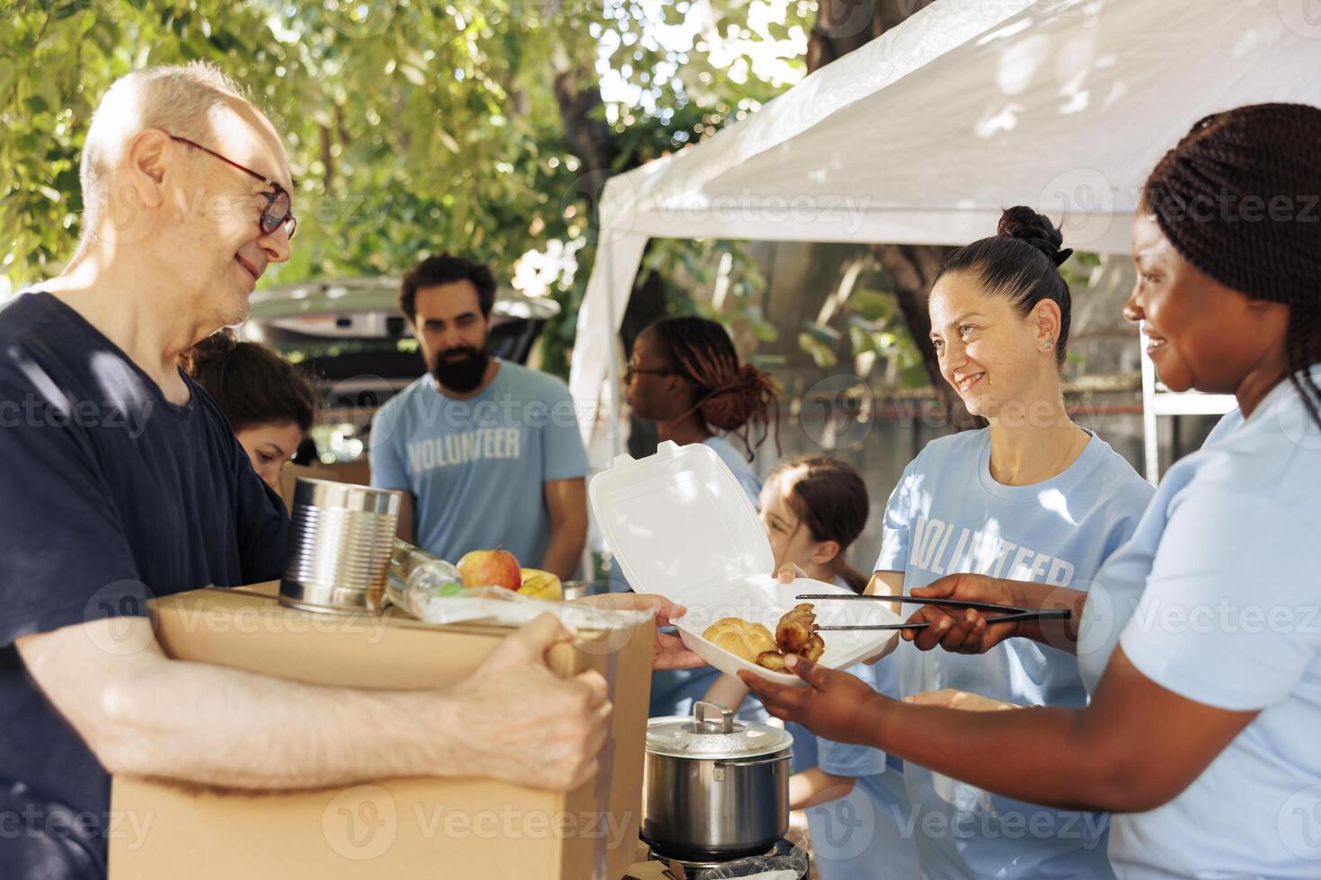 Charity wokers happily provide food donations to the poor, including homeless individuals and seniors. Hunger relief team distribute meal boxes and packages of canned goods with genuine smiles. photo