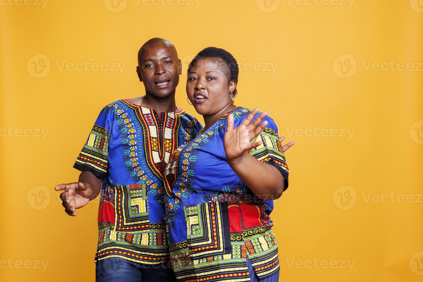 Man and woman couple dancing and singing together while looking at camera. Mid adult african american wife and husband pair making moves and talking while posing for portrait photo