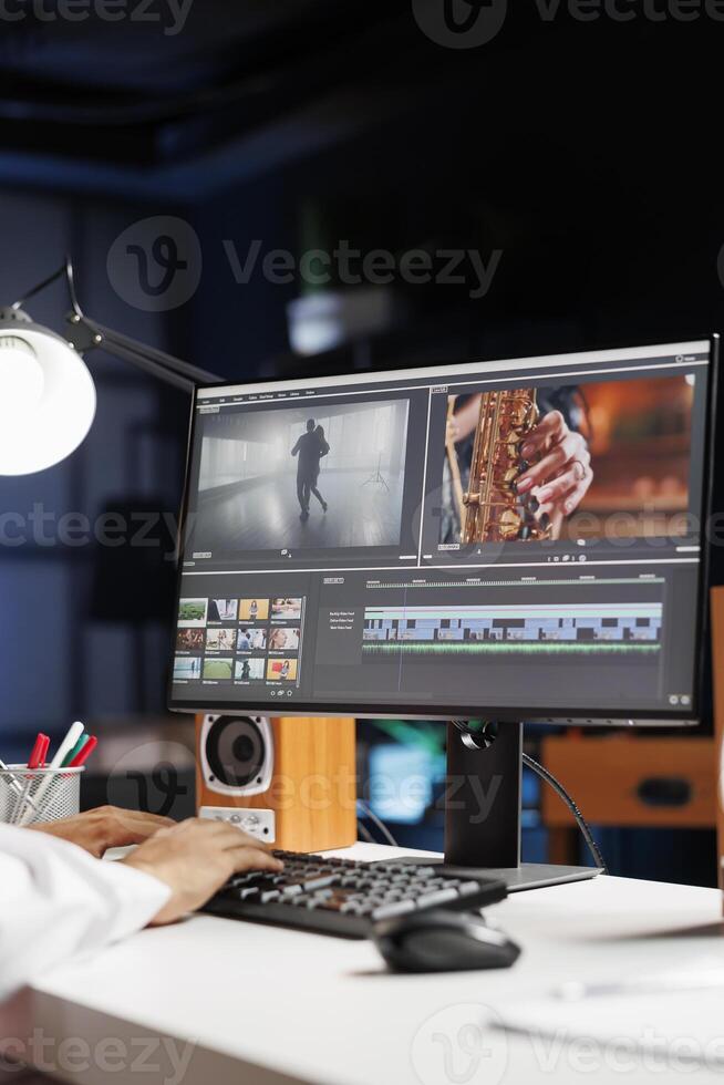 Male cinematographer working with footage and sound, editing new project, cutting film montage seated at office desk. Detailed view of man using computer processing movie in post production software. photo