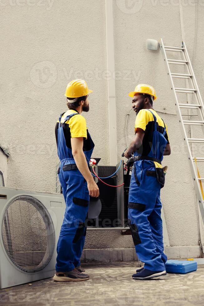 preciso militares haciendo anual externo aire acondicionador chequeo, preparando presión medición dispositivo. meticuloso trabajadores equipo comprobación para refrigerante fugas líder a reducido enfriamiento eficiencia foto