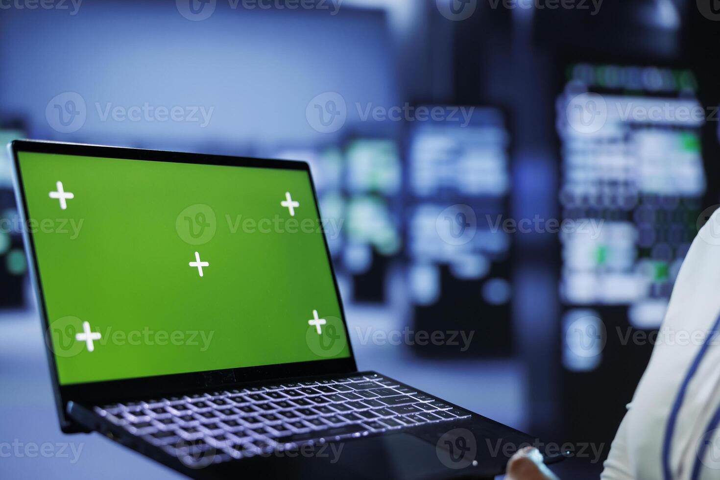 Admin in data center uses mockup laptop to prevent server machines overload. Expert between server mainframes using isolated screen device to ensure enough network bandwidth for smooth operations photo