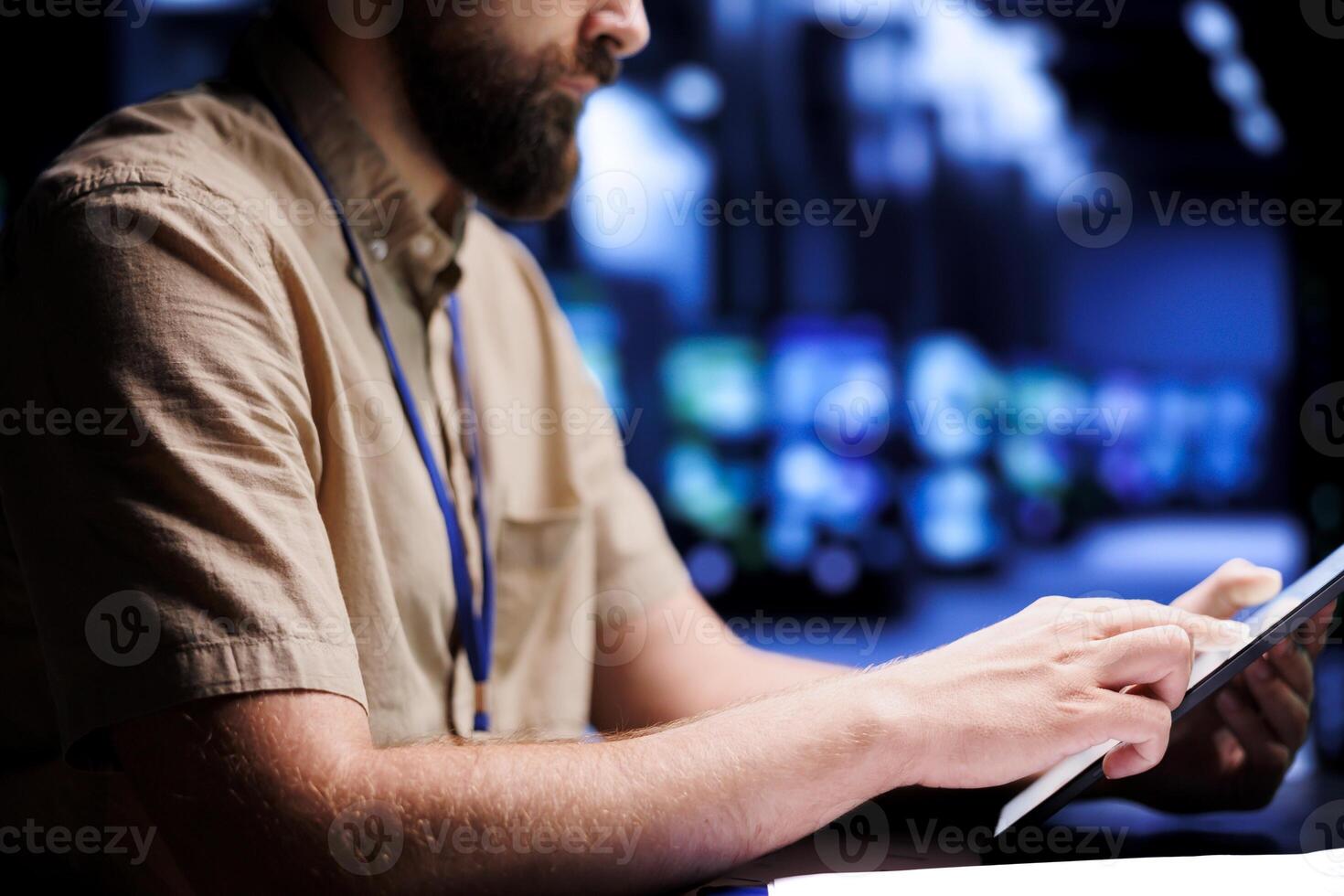 Certified electrician using tablet to examine blade servers for power fluctuations. Licensed professional monitoring data center devices, identifying potential vulnerabilities, close up photo