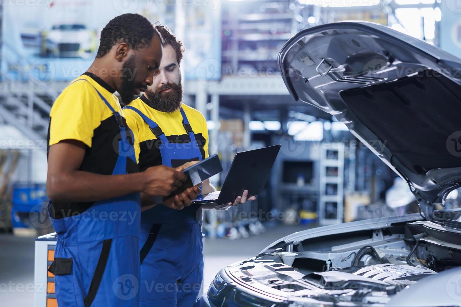 Coworkers in car service using tablet to calculate repairments invoice for client after fixing damages. Teamworking experts using devices to determine final costs after servicing vehicle photo