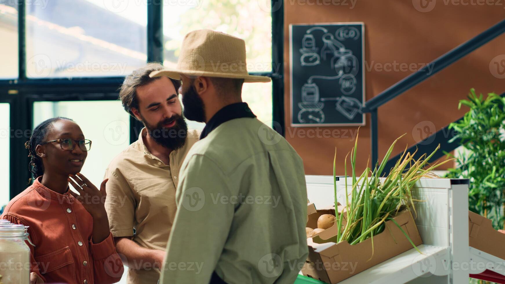 Customers asking about organic products stored in crates at local zero waste eco supermarket. Storekeeper recommending healthy eating chemicals free alternatives to vegan people shopping. photo