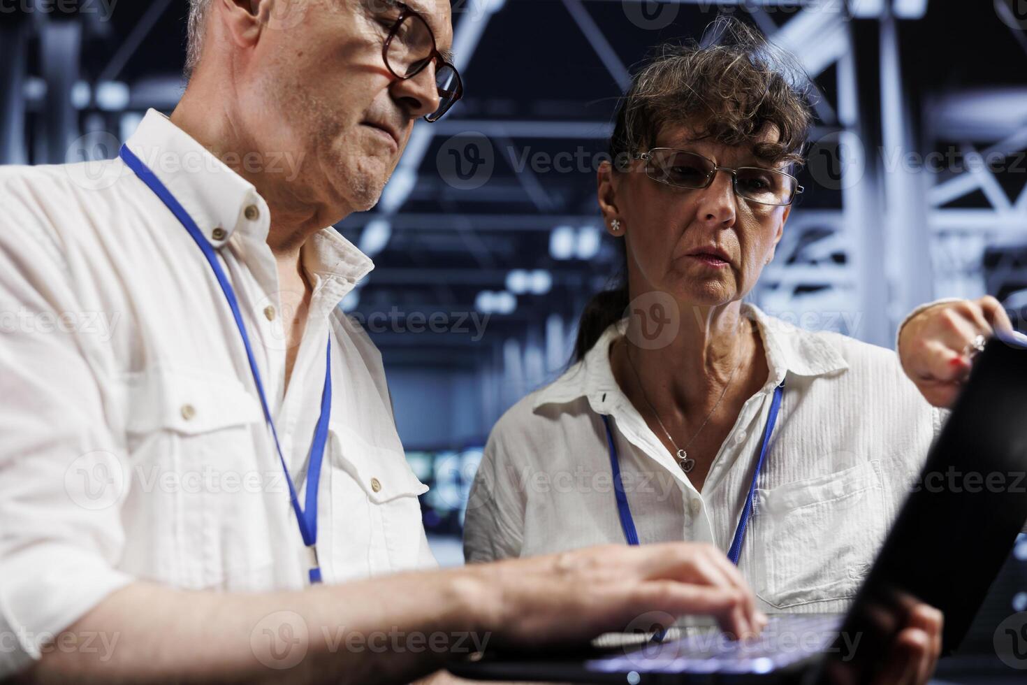 Senior teamworking colleagues running analysis on server cabinets helping businesses manage databases, host websites and store files. Proficient mechanics auditing high tech data center units photo
