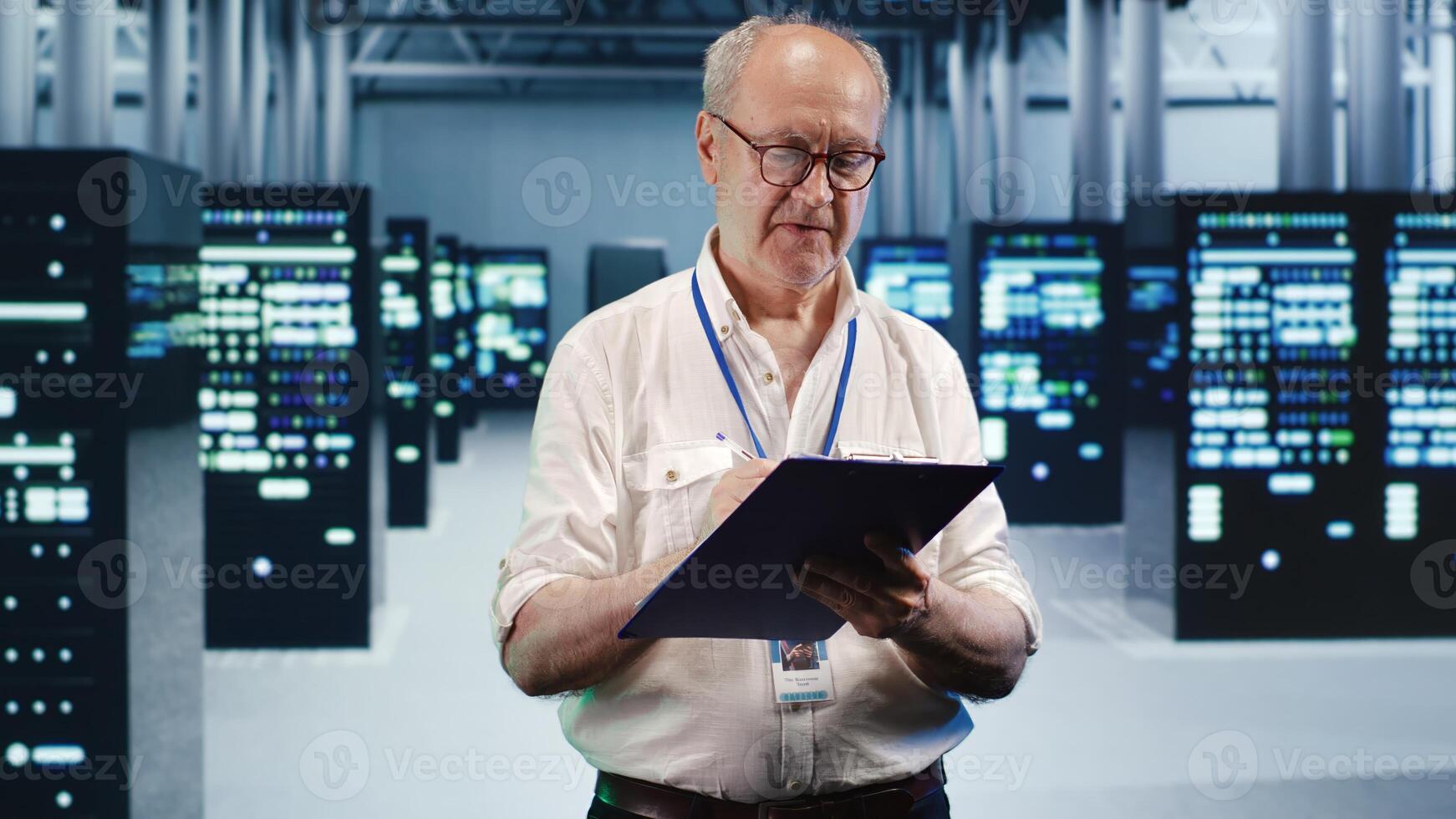Senior technician looking around high tech data center, using clipboard to crosscheck disaster recovery plan and assess server parts in need of replacement, preventing damages photo