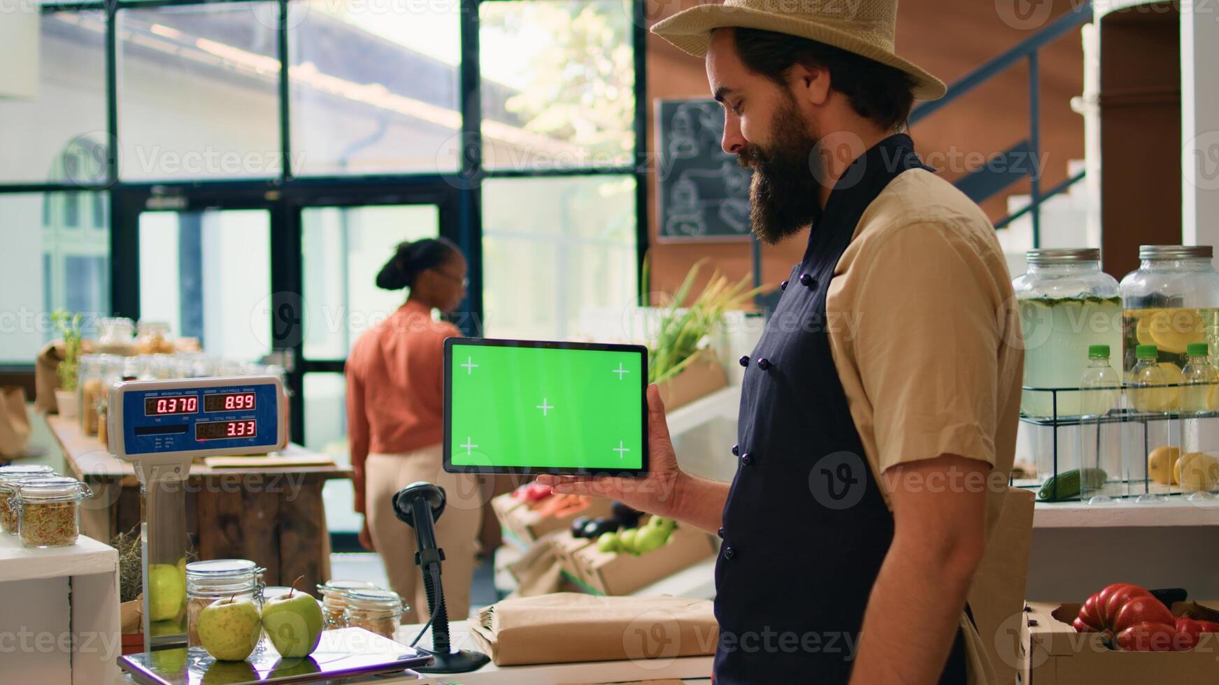 Storekeeper holds tablet with greenscreen in zero waste eco supermarket, using copyspace mockup on mobile gadget standing at checkout counter. Small business owner presents isolated display. photo