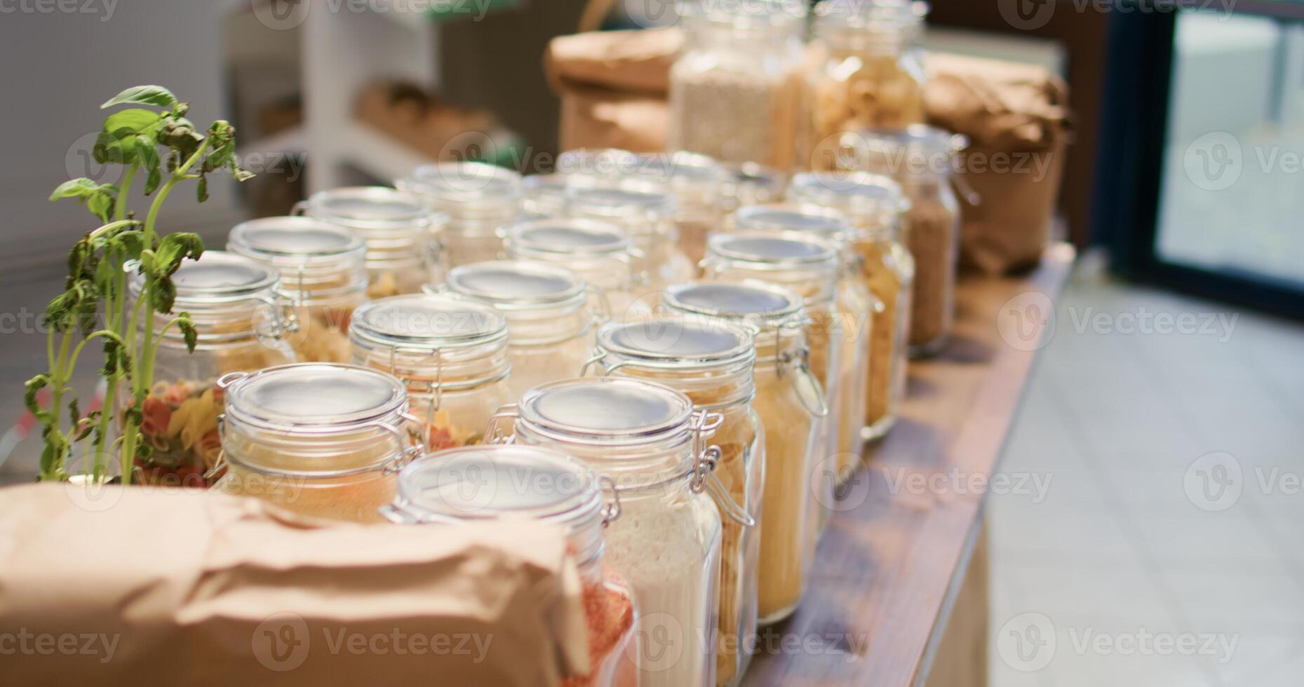 Close up on bulk food items in glass jars used by environmentally friendly zero waste store to lower climate impact. Local organic shop with natural ingredients pasta, spices or sauces. photo