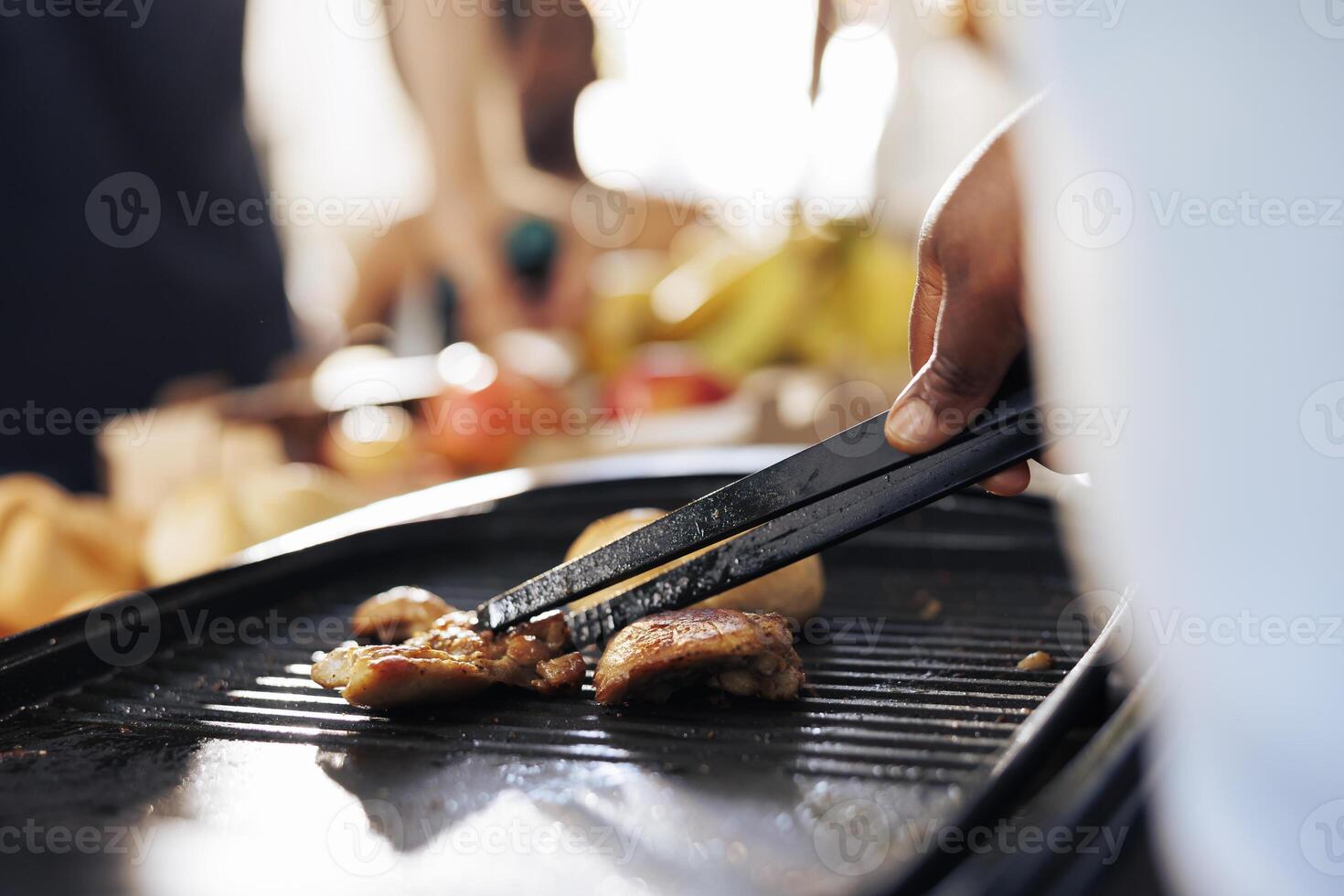 African american individual prepares meals on grill highlighting humanitarian aid efforts in alleviating hunger and poverty. Detailed shot captures charitable act of cooking for the less fortunate. photo