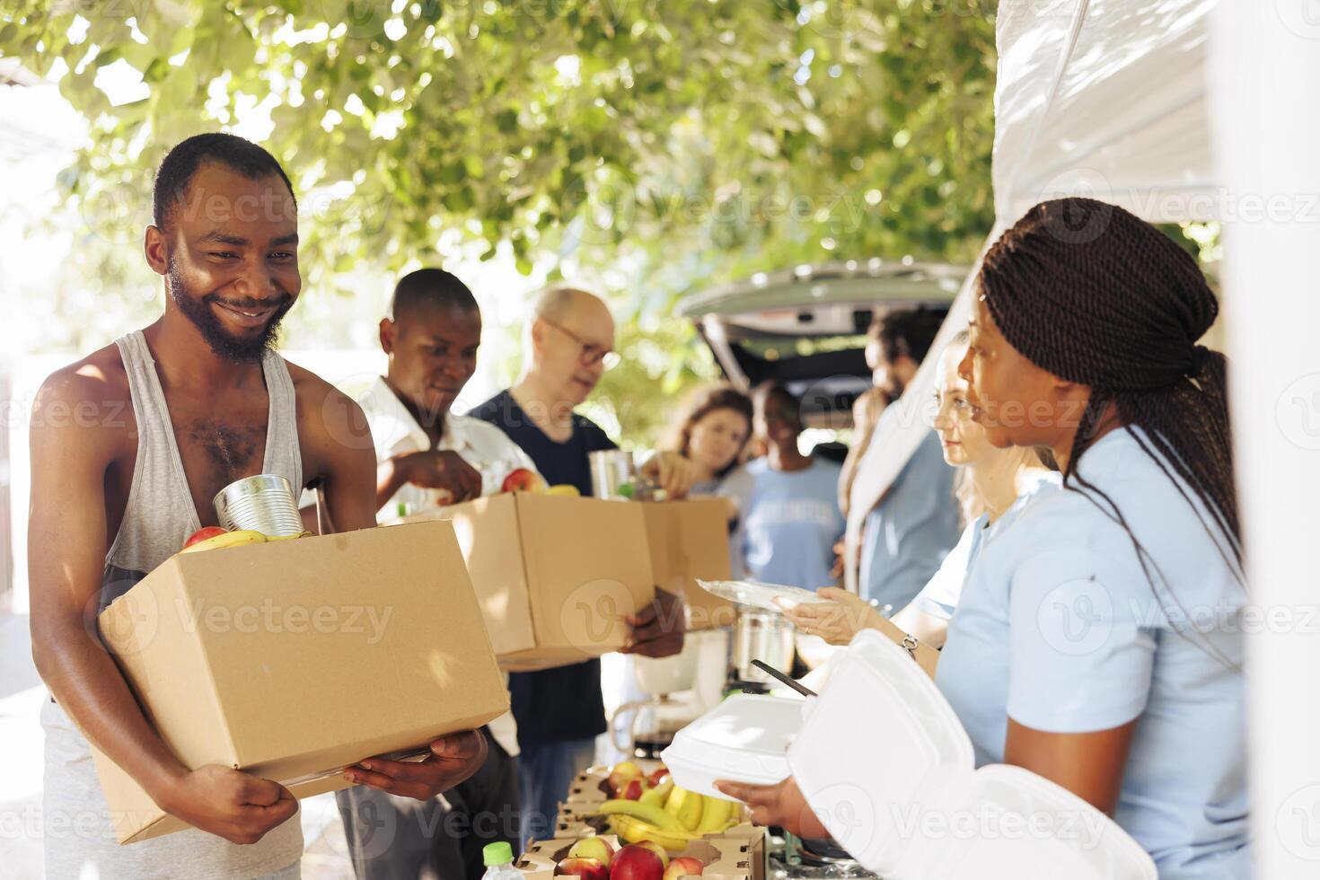 Smiles and teamwork shine through as volunteers provide assistance to the homeless and individuals facing poverty. Image captures the heartwarming impact of charity and food drives. photo