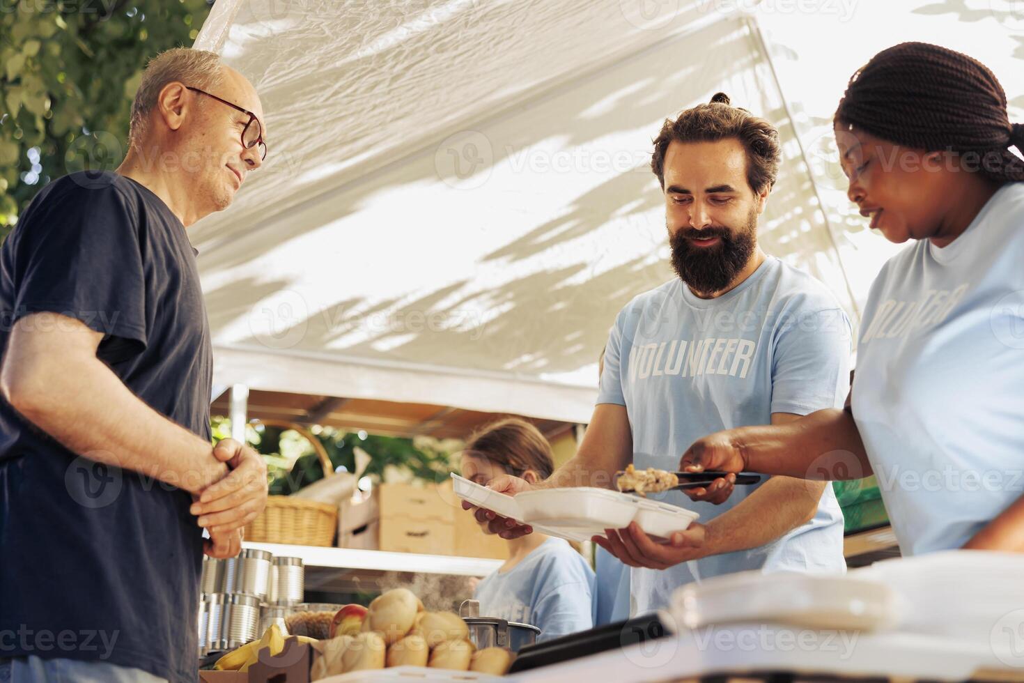 negro mujer y caucásico hombre trabajando juntos a organizar comida distribución para hambre alivio iniciativa. multirracial voluntarios servicio caliente comida desde comida banco a hambriento Vagabundo hombre. foto