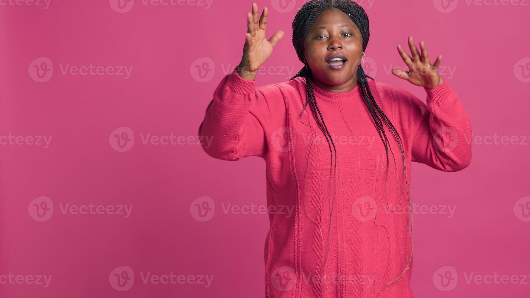 Young black woman displeased and saying no at camera with hands raised. African american fashion blogger having disappointed self expression positioned against pink background. photo
