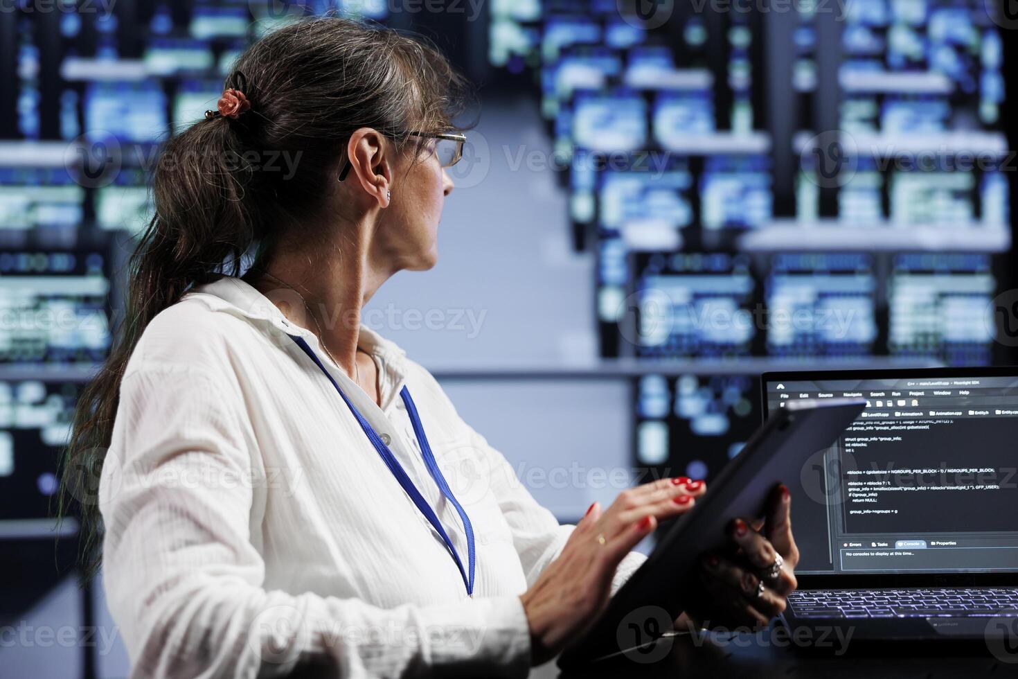 Elderly programmer writing script code in data center on laptop terminal. Proficient specialist doing maintenance work in server farm, updating rigs software to prevent malfunctions photo