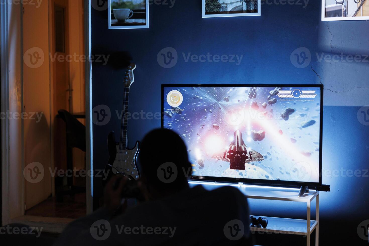 Young adult enjoying time playing shooter games on tv, plugging his console to television in the living room and spending game session at night. Man engaging in first person shooting contest. photo