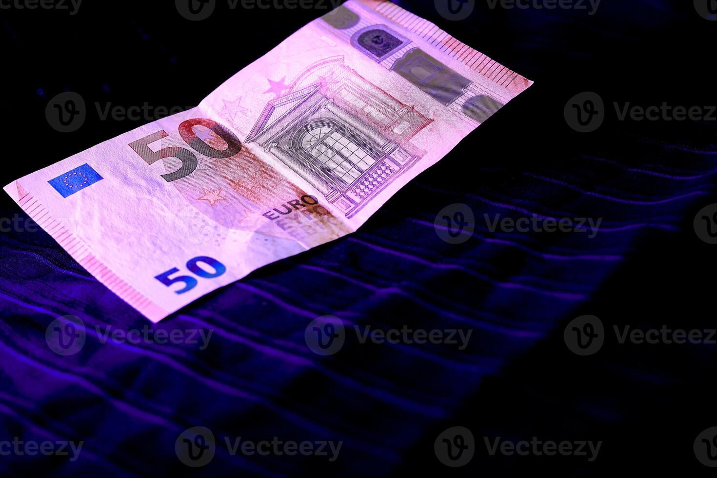 Money. 50 euro banknote being examined under ultraviolet light on a dark cloth photo