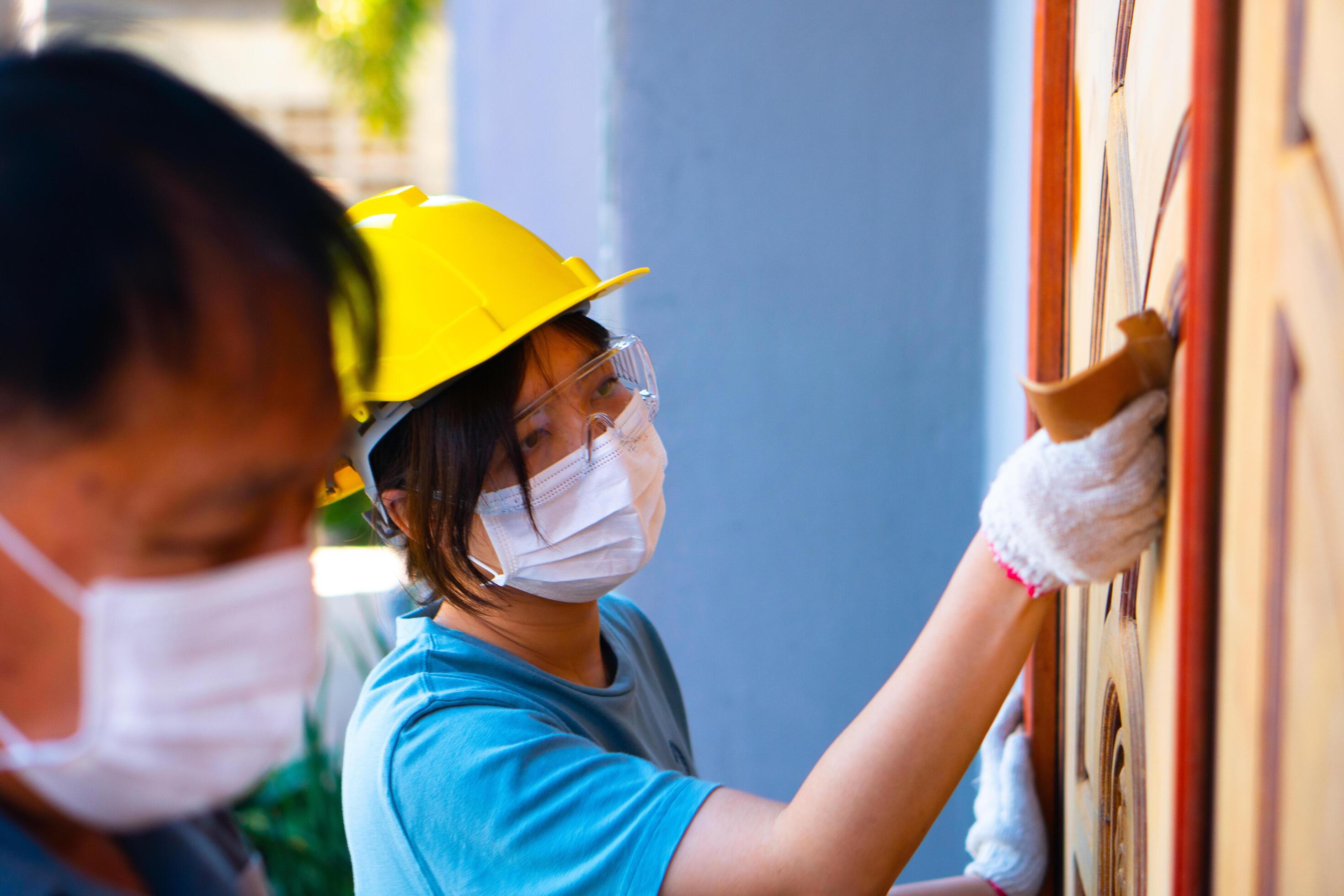A team family worker Using sandpaper to polish a wooden door at home