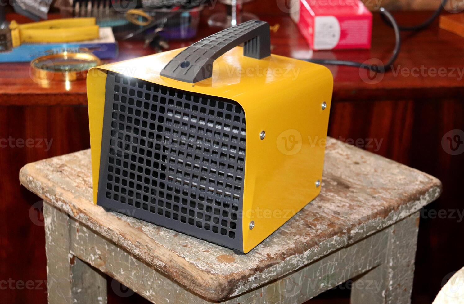 An electric heat gun for heating a room on a shabby stool in a village house. Electrical appliance, horizontal photo, side view photo