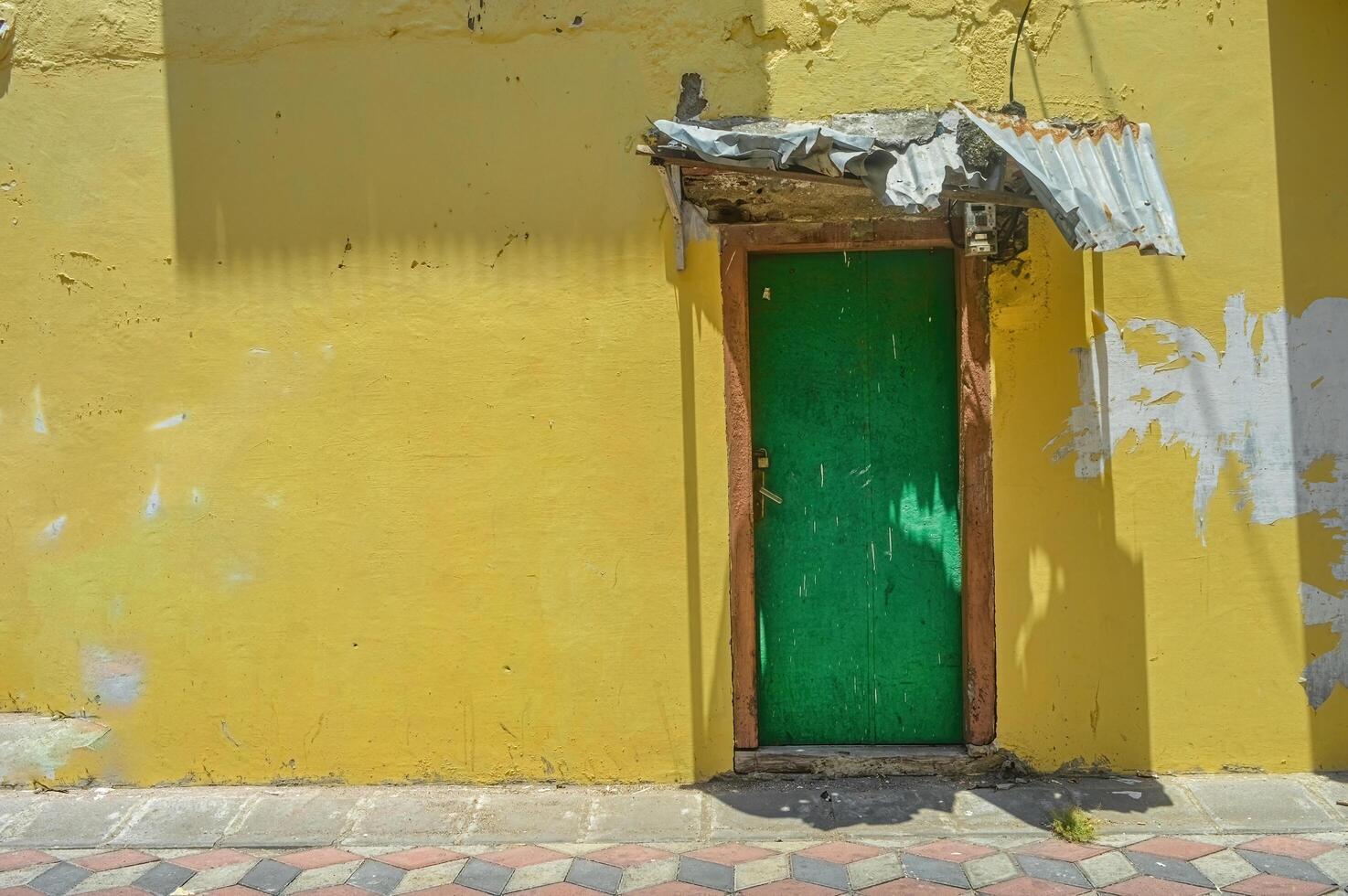 a green wooden door with yellow walls showing some of the peeling paint on the old house photo