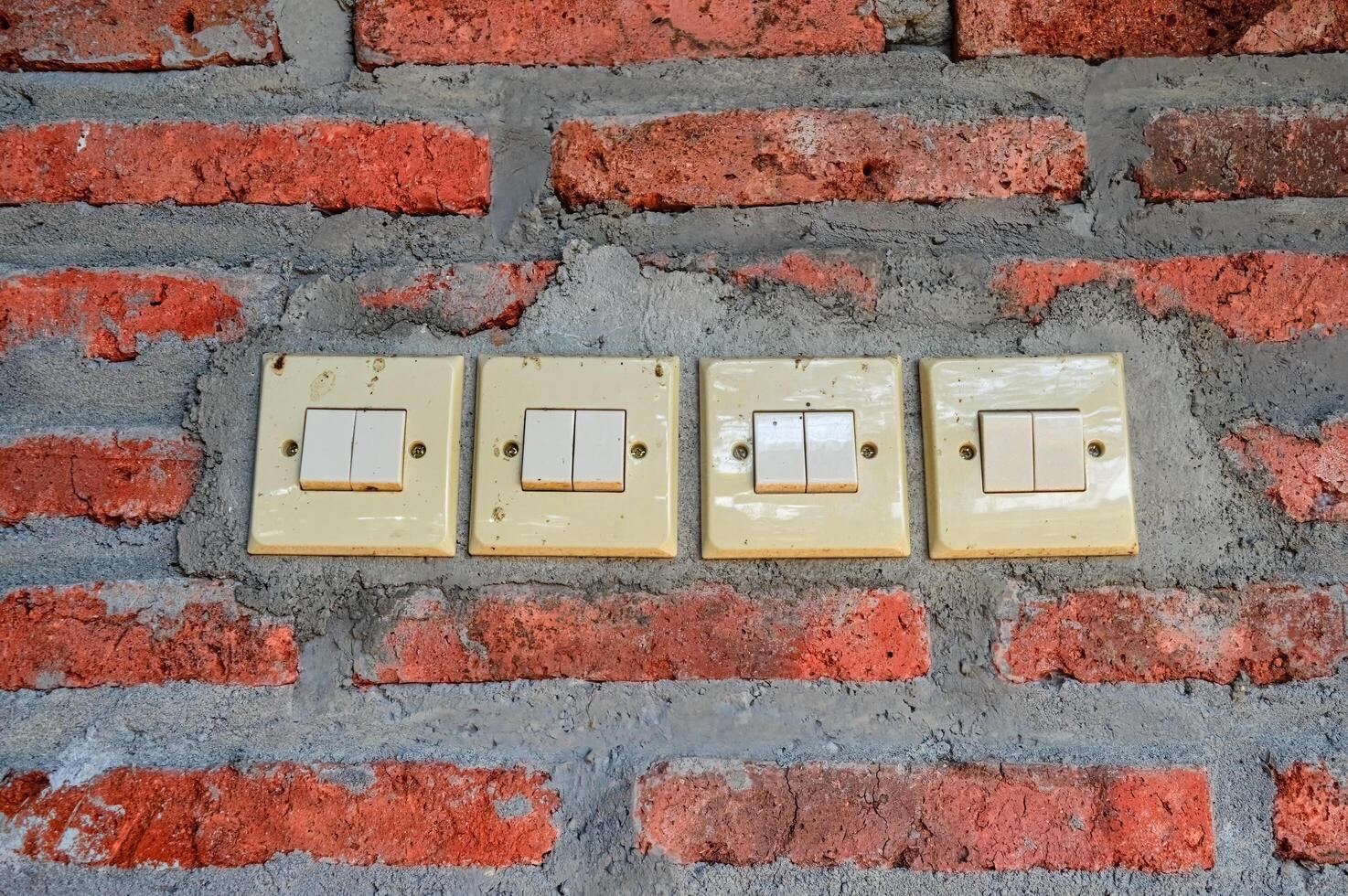 four double switches attached to the red brick wall photo