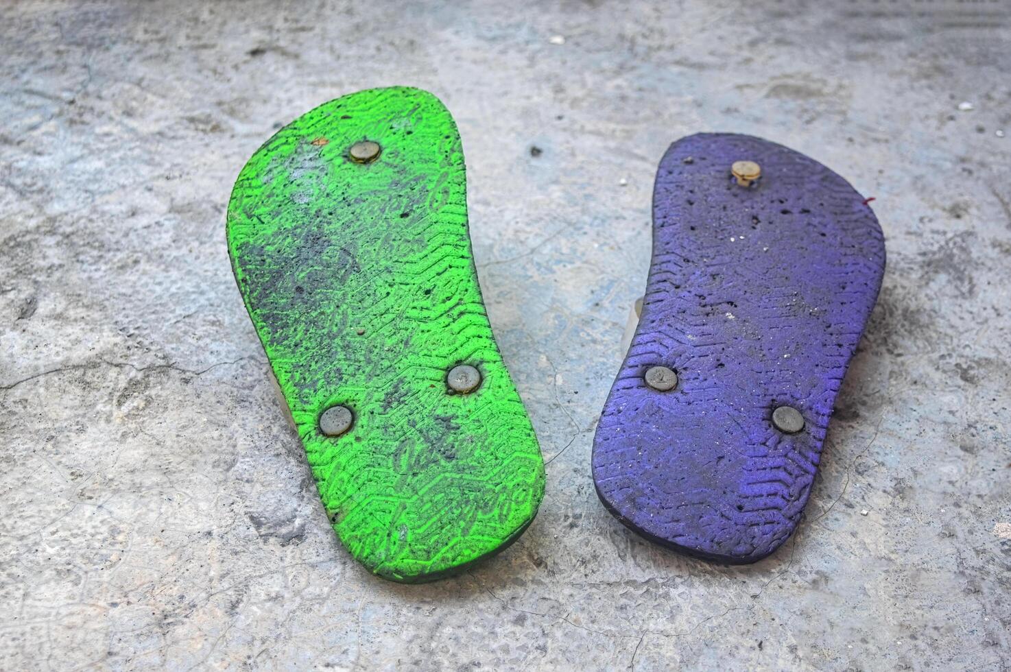 a pair of purple and green flip-flops placed upside down photo