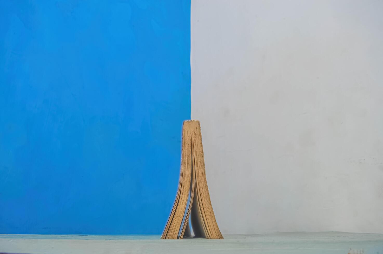 a thick book open upside down against the backdrop of a divided blue and white wall photo