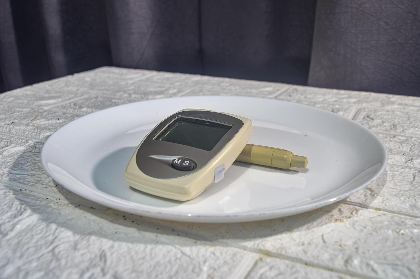 glucose, cholesterol and uric acid test equipment with a syringe on a dinner plate photo